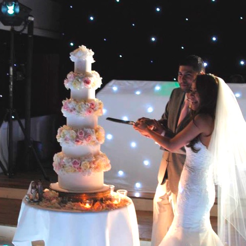 Couple cutting wedding cake with cake topper